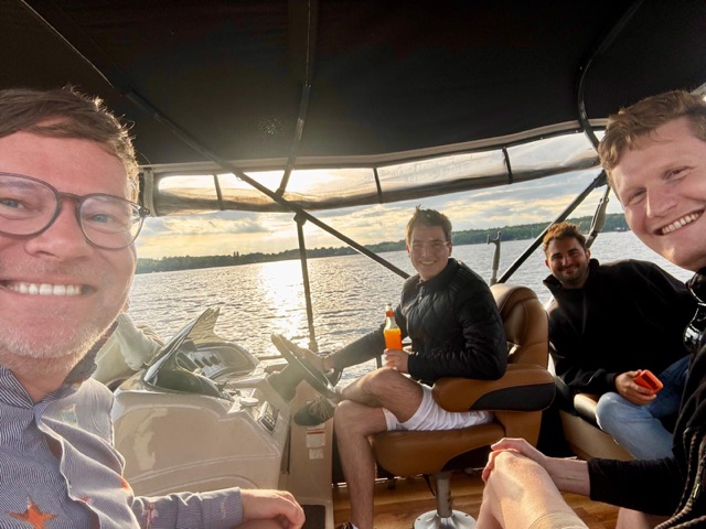 Four of the team on a boat on the lake at sunset